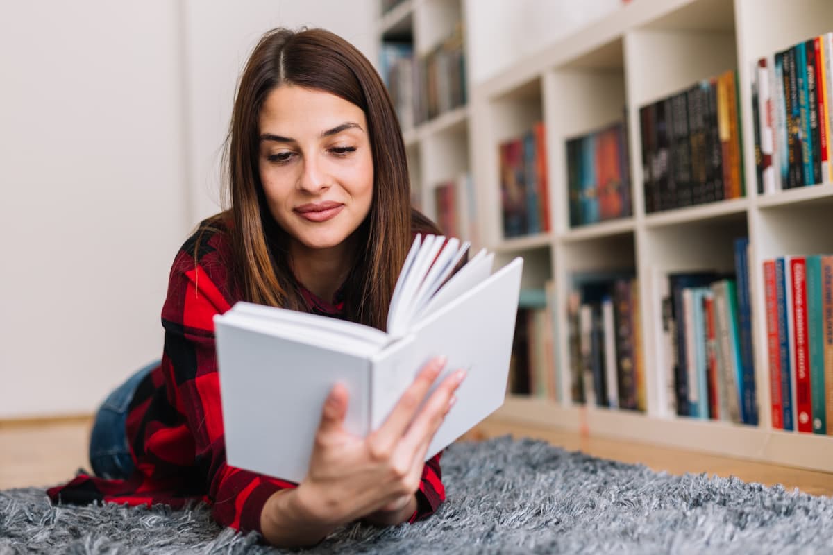 Woman reading book, lying on the floor
