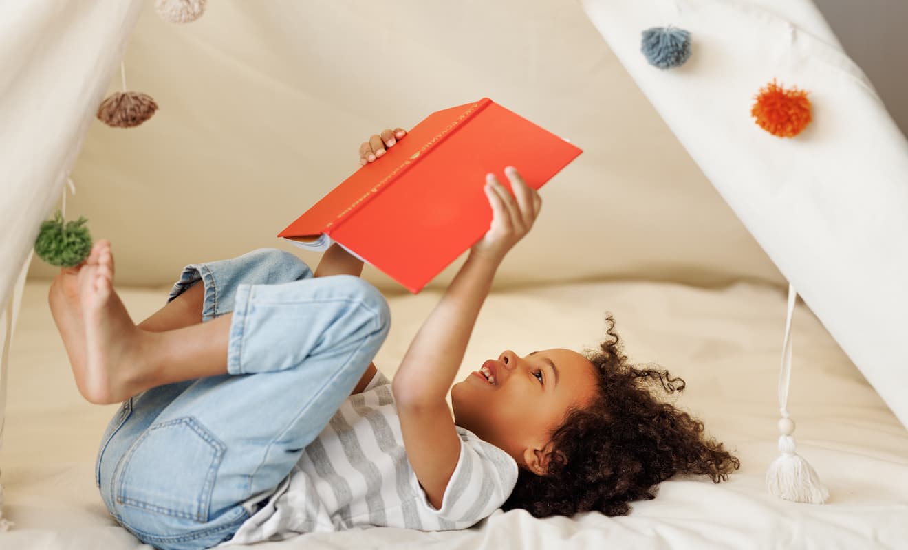 Child reading a book in a play tent