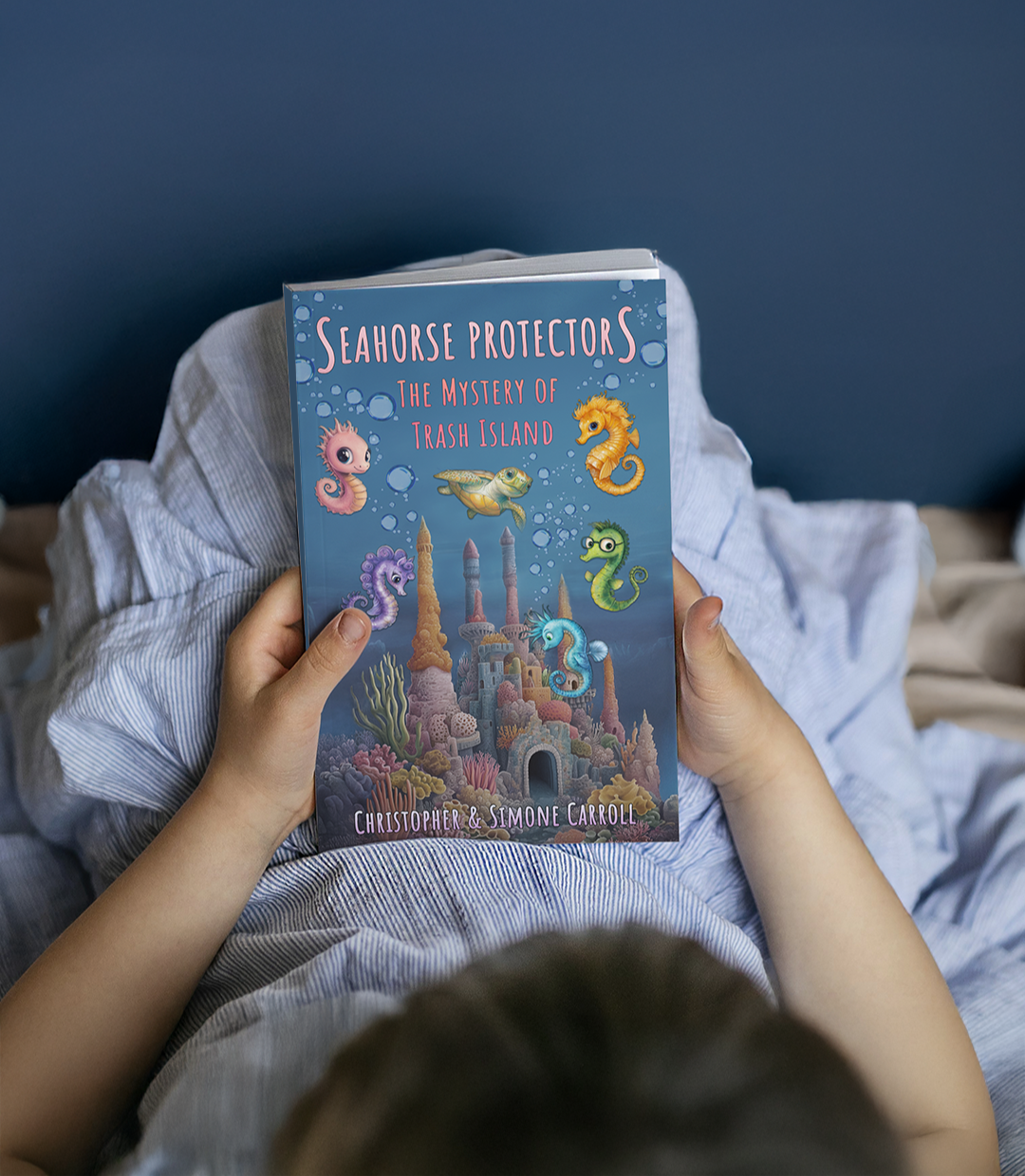 Seahorse Protectors by Christopher Carroll and Simone Carrroll for Tribus Press book held by child in bed
